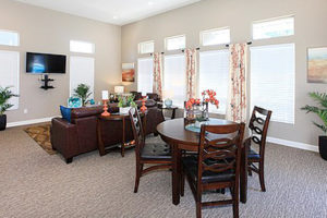 Resident lounge with seating area with table, couches, television, bright windows, and decorations